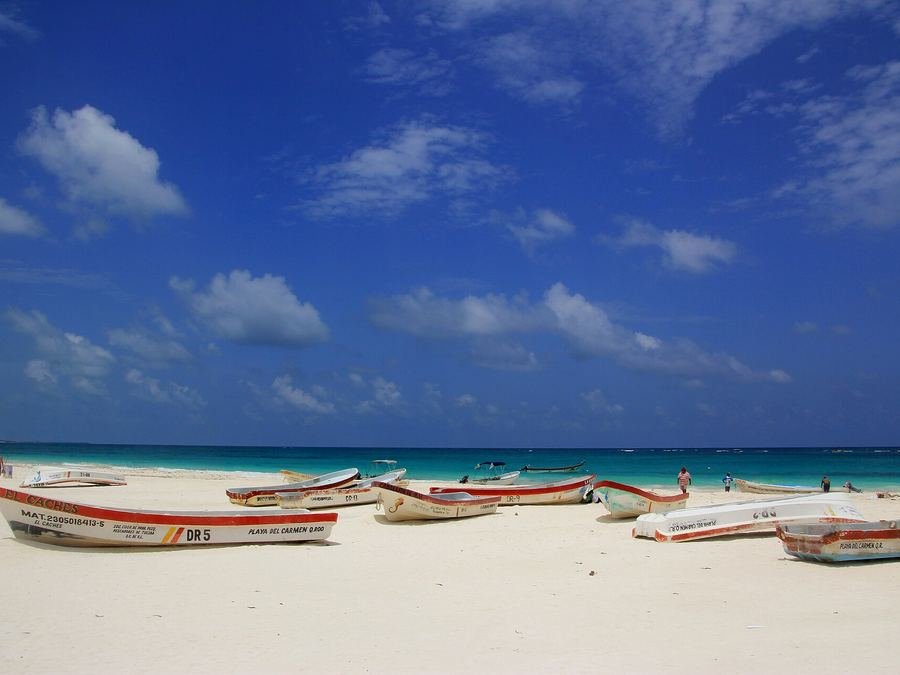 Lanchas de pescadores sobre la arena blanca de una playa de Tulum con mar turquesa